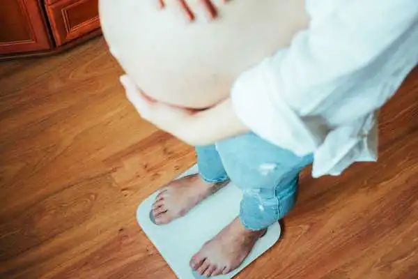Image of woman weighing herself and experiencing weight gain through pregnancy Runnymede